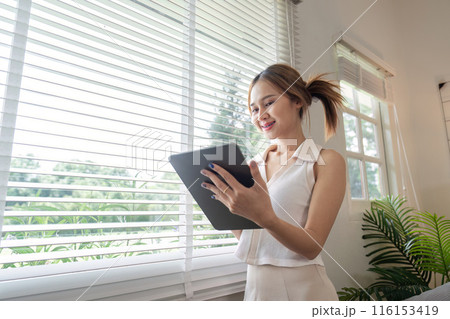 Young Woman Relax at Home with Tablet by the Window in Bright Modern Living Room 116153419