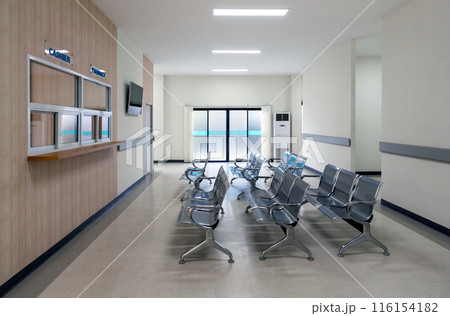 An empty waiting area with chairs, a cashier sign, and a pharmacy window in a modern building. There are rows of connected grey seating for individual waiting. Glass door at the back lead to the exit 116154182