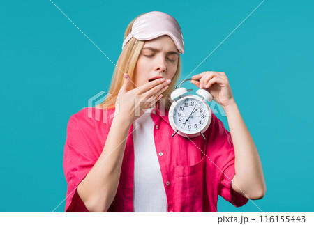 Woken up by alarm clock sleepy young woman holding it in hand. Blue background Woken up by alarm clock sleepy young woman holding it in hand. Blue background 116155443