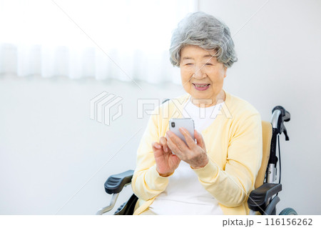 スマホを操作する車椅子のシニア女性 スマホを操作する車椅子のシニア女性 116156262