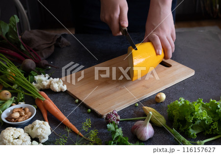 Close up of young woman hands cutting zucchini on wooden cutting board at home. Young woman preparing healthy food. Close up of young woman hands cutting zucchini on wooden cutting board at home. Young woman preparing healthy food. 116157627