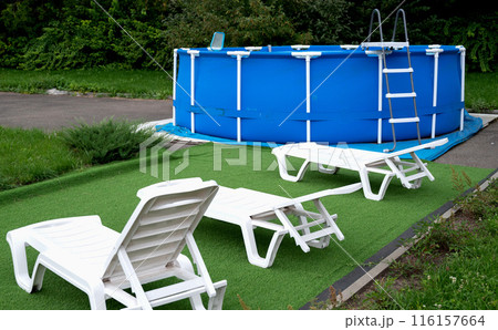 Blue portable country pool on the lawn of a country garden. Swim activity in backyard of country house. Summer, relaxation. 116157664
