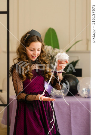 Girl examining pearls and smiling at birthday party 116157675