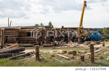 Wooden a log houses under construction with building materials lying nearby Wooden a log houses under construction with building materials lying nearby 116157696