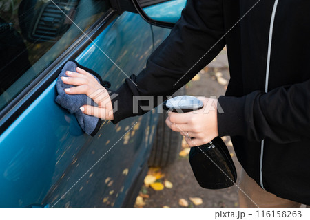 Closeup picture, image young woman, driver, dry wiping her car with microfiber cloth after washing it, cleaning auto, automobile windows. Transportation self service, care concept. Paint protection Closeup picture, image young woman, driver, dry wiping her car with microfiber cloth after washing it, cleaning auto, automobile windows. Transportation self service, care concept. Paint protection 116158263