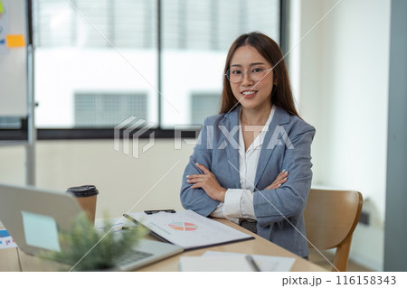 Confident Businesswoman in Office with Laptop and Documents, Smiling and Ready for Work 116158343