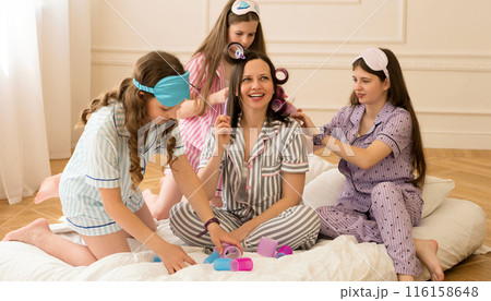 Woman in striped pajamas gets hair done by girls 116158648