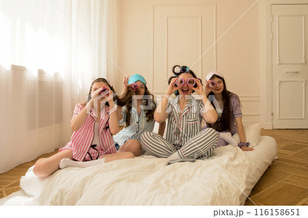 Girls and mom pretend to use curlers as binoculars. 116158651