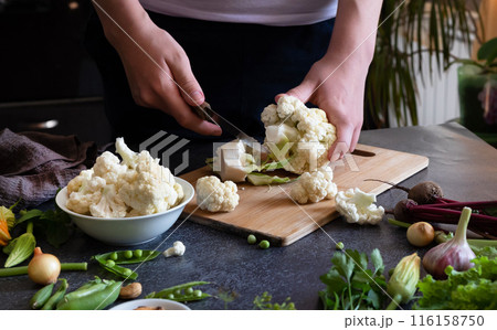 A woman cuts fresh cauliflower at the table 116158750
