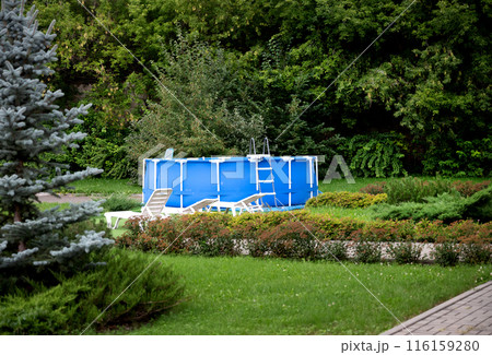 Blue portable country pool on the lawn of a country garden. Swim activity in backyard of country house. Summer, relaxation. 116159280