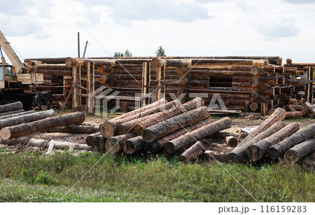 Wooden a log houses under construction with building materials lying nearby 116159283