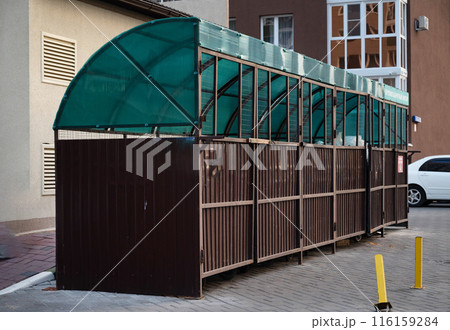 Six new plastic green garbage standard containers. Back side of the city sports festival. In the background - trading canvas tents 116159284