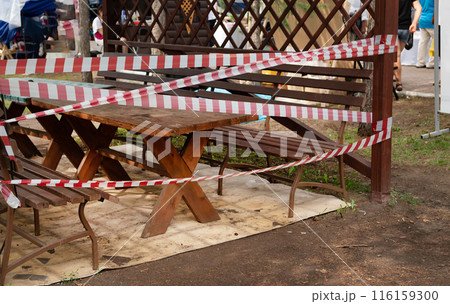 Slide on empty playground in park fenced with red and white attention tape during COVID 19 epidemic 116159300