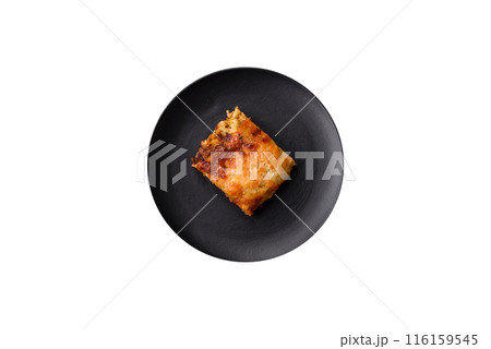 Delicious baked lasagna pasta with meat, sauce, salt, spices and herbs on a dark concrete background Delicious baked lasagna pasta with meat, sauce, salt, spices and herbs on a dark concrete background 116159545