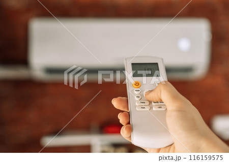 Remote control of a white air conditioner that hangs on a brick wall Remote control of a white air conditioner that hangs on a brick wall 116159575