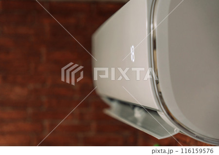 White air conditioner cools the air and hangs on a brick wall White air conditioner cools the air and hangs on a brick wall 116159576