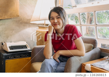 Woman in red is sitting casually in the cozy flowing living room. Woman in red is sitting casually in the cozy flowing living room. 116160813