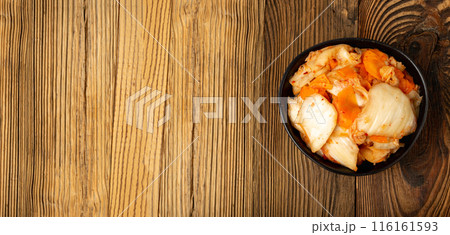 Kimchee in black bowl on wood table. Spicy kim chi pile, hot fermented napa cabbage, traditional jimchi 116161593