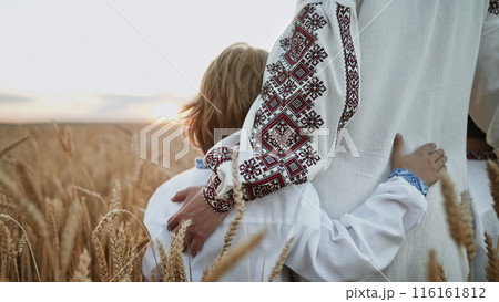 Mom hugs, strokes sons head.Unrecognizable ukrainian young family in wheat field 116161812