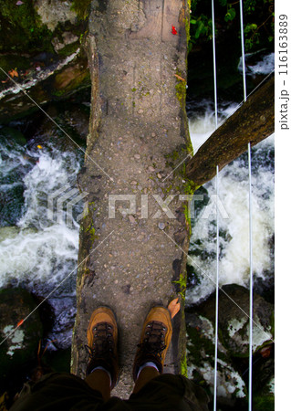 First-Person View of Hiking Boots on Wooden Bridge Over River in Tennessee 116163889