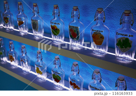 Artisan Glass Vape Bottles on Illuminated Shelves with Vibrant Labels 116163933
