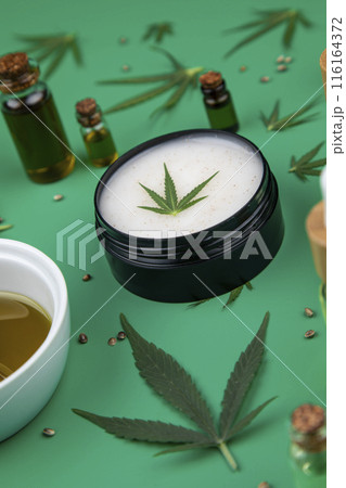 Flat lay composition with hemp oil and hemp leaves on green color background 116164372