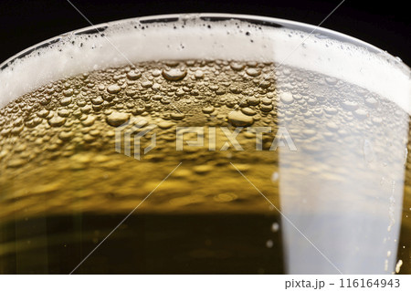 light golden beer in a glass glass on a black background 116164943
