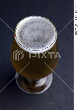 light golden beer in a glass glass on a black background 116164945