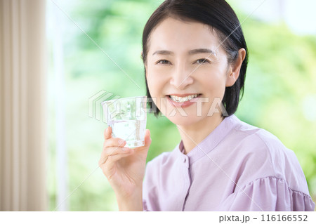 リビングで水を飲む笑顔のミドル女性 116166552