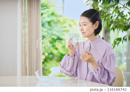 リビングで薬を飲む笑顔のミドル女性 リビングで薬を飲む笑顔のミドル女性 116166742
