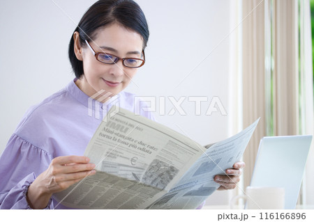 老眼鏡を掛けて英字新聞を読むミドル女性 116166896