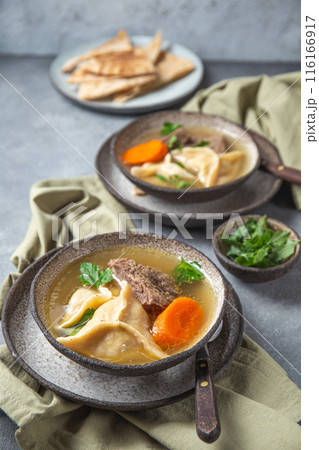 Traditional Jewish Kreplach soup with meat and carrot, gray background Traditional Jewish Kreplach soup with meat and carrot, gray background 116166917