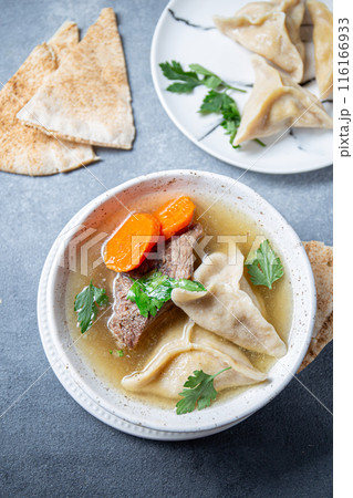 Traditional Jewish Kreplach soup with meat and carrot, gray background 116166933
