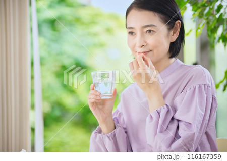 リビングで薬を飲む笑顔のミドル女性 リビングで薬を飲む笑顔のミドル女性 116167359