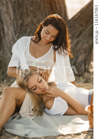 Women Relaxing Together On Picnic Blanket In Forest Women Relaxing Together On Picnic Blanket In Forest 116167861