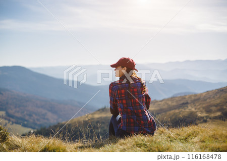 Woman Relaxing on Grass with Stunning Mountain Panorama 116168478