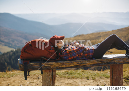 Female Hiker Relaxing on Bench in Scenic Mountain Landscape 116168479