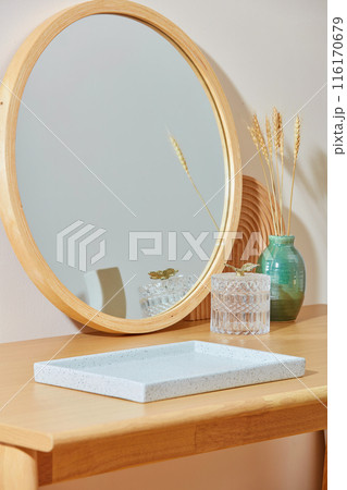 A large empty tray in white color displayed on a wooden table, behind it is decorated with a big mirror, a glass pot and a flower vase. Photo has diagonal angle, copy space for text A large empty tray in white color displayed on a wooden table, behind it is decorated with a big mirror, a glass pot and a flower vase. Photo has diagonal angle, copy space for text 116170679