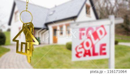 Image of gold house key fob and key, hanging in front of blurred house with sold sign Image of gold house key fob and key, hanging in front of blurred house with sold sign 116171064
