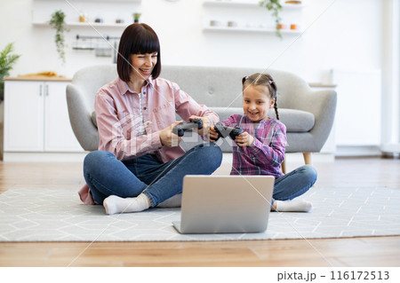 Mother and daughter playing video games together 116172513