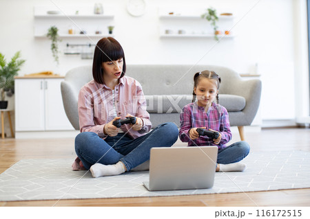 Mother and daughter playing video game together at home 116172515