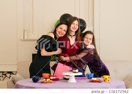 Teen girl hugging woman and young girl. 116172562