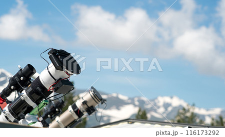 Telescopes on observatory rooftop with mountain view. Telescopes on observatory rooftop with mountain view. 116173292