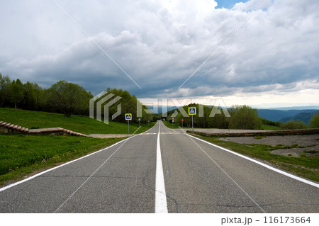 Straight road leading into distance with cloudy sky. Straight road leading into distance with cloudy sky. 116173664