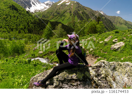 Girl resting on rock with alpine view and mountain stream 116174453