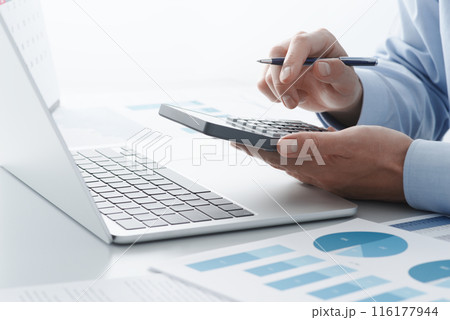 電卓やノートパソコンを使って税金の計算をする男性。確定申告や年末調整など税の申告。 116177944