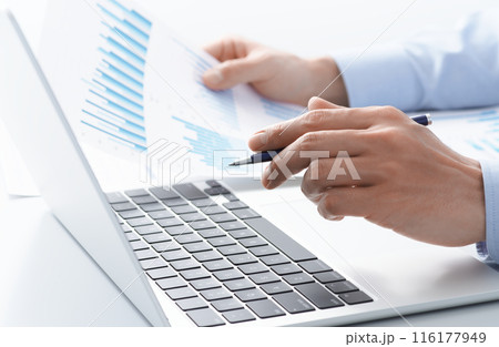 個人事業の財務データ分析。ノートパソコンを使いレポートを精査している経営者の手のアップ。 116177949