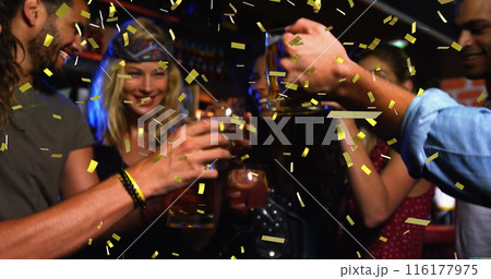 Friends holding drinks, celebrating together at lively bar 116177975