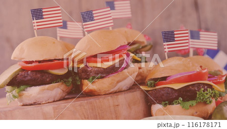 Four burgers, each topped with American flag, resting on wooden board Four burgers, each topped with American flag, resting on wooden board 116178171