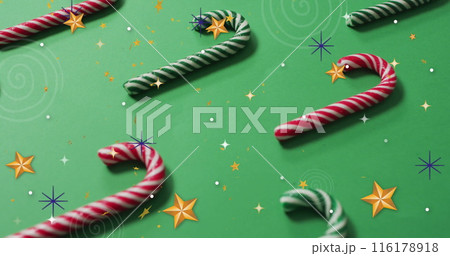 Image of stars over candy canes on green backrgound 116178918